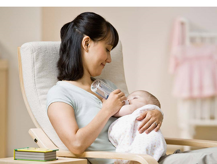 Woman Feeding Bottle to Infant